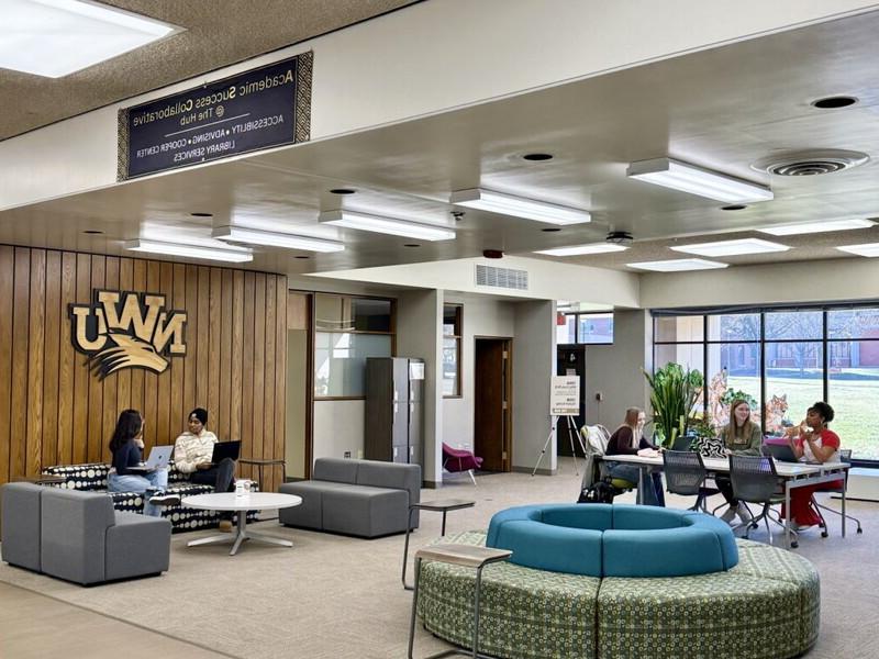 The first floor of the library has students sitting in spaces studying.