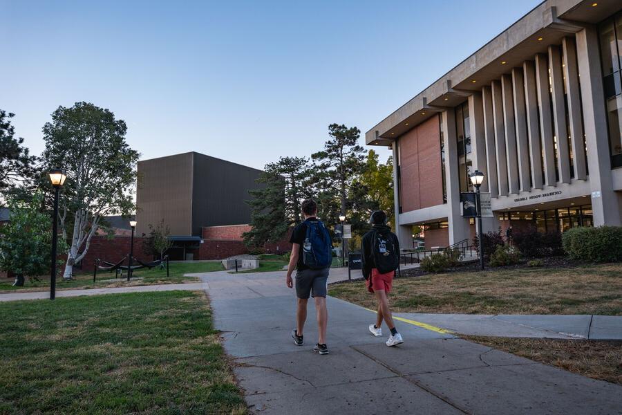 Two students walking at night in front of the library.